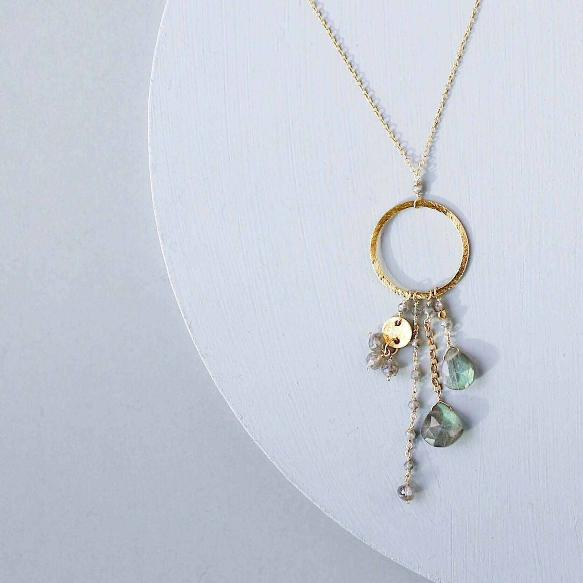 The Ammil Necklace featuring a labradorite gemstone pendant with multi-strand gemstone details on a 14k gold plated hoop.