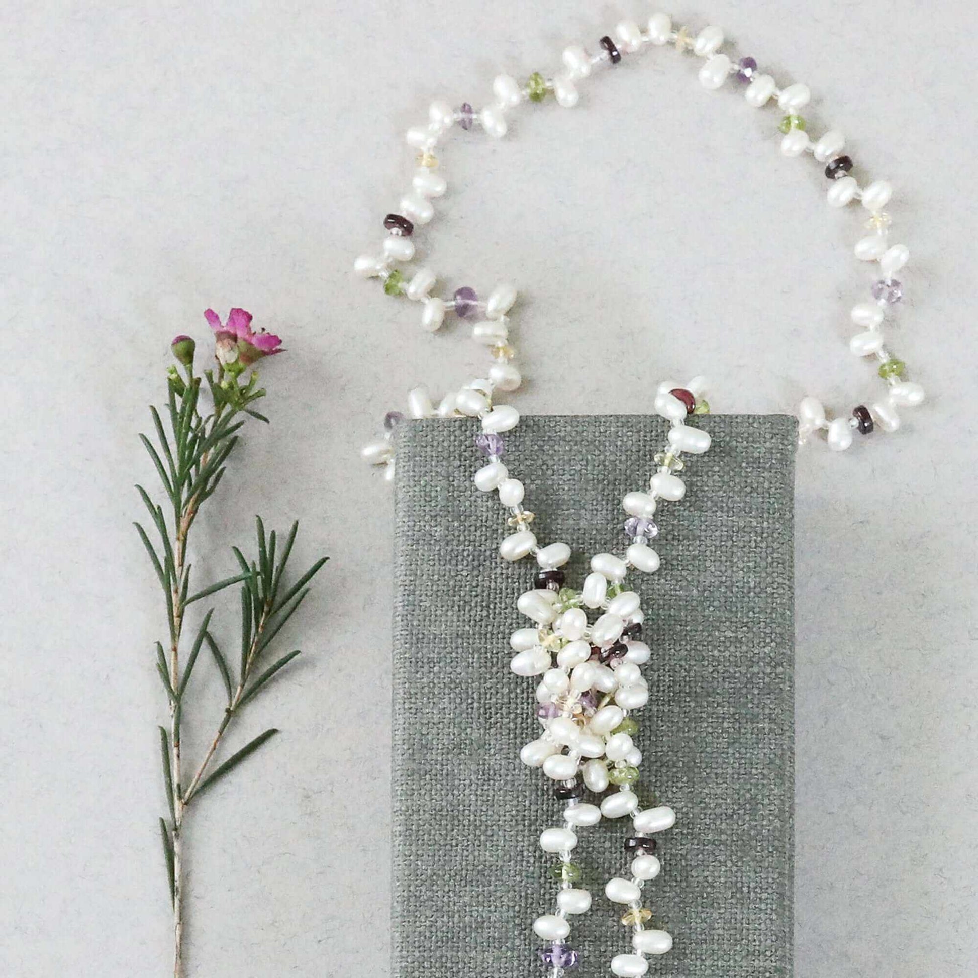 Pearl and gemstone ballet lariat necklace with freshwater pearls and multicolored gemstones displayed on white background