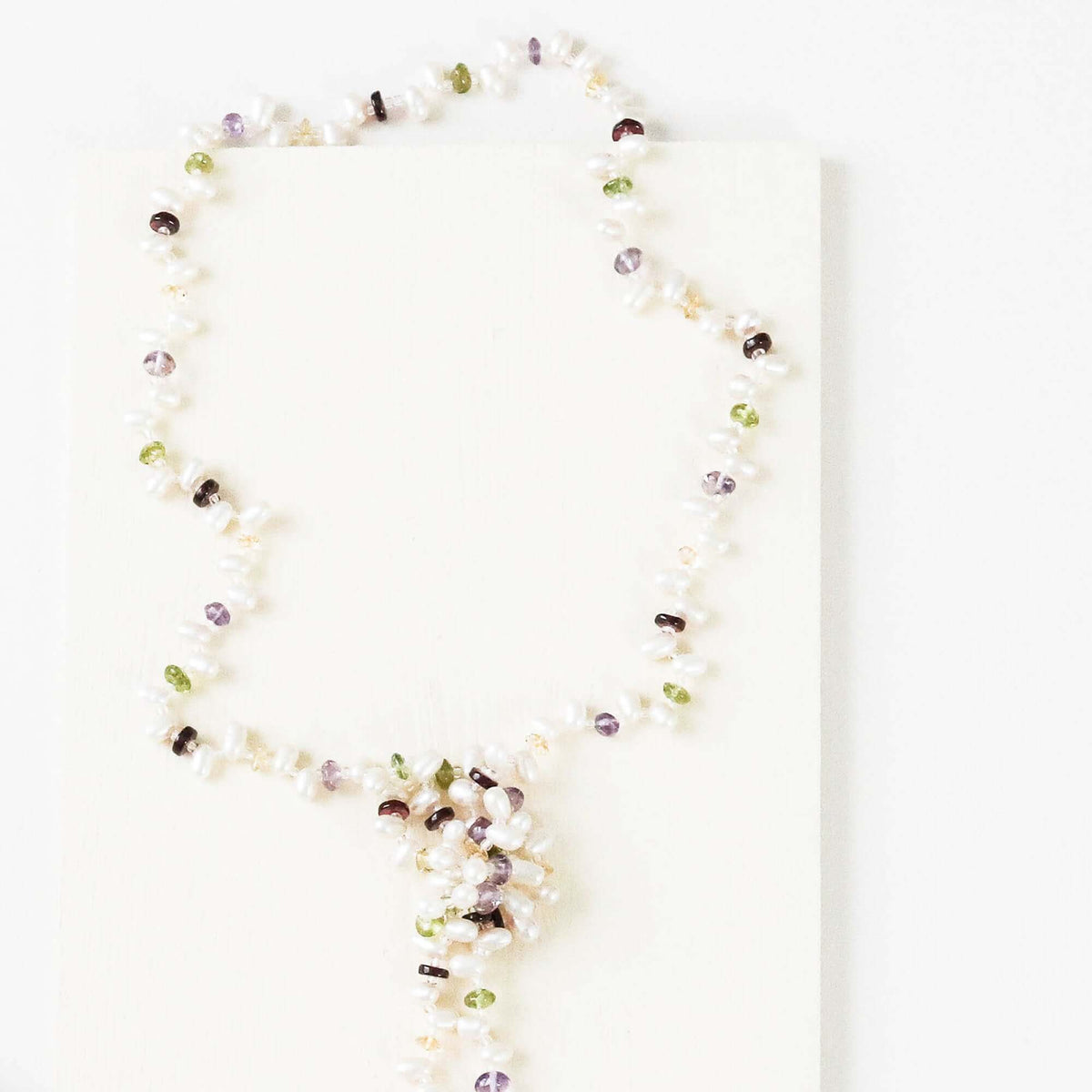 Pearl and gemstone ballet lariat necklace with freshwater pearls and multi-colored gemstones on a white background
